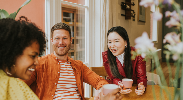 adult millenials sitting around a table laughing and talking