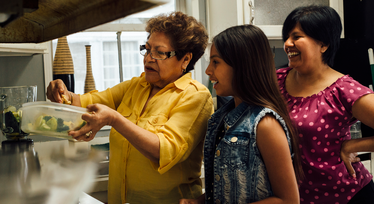 girl with long hair and two women with shorter hair preparing a meal in a kitchen