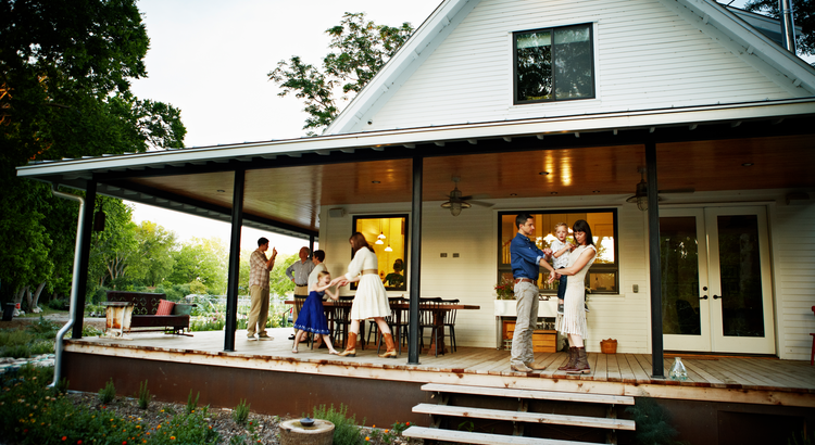 multi generational family enjoying each other's company on the front porch of a house