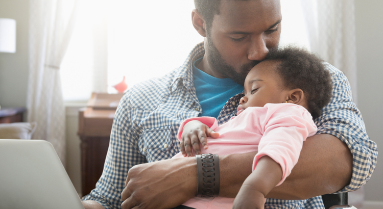 father holds his baby girl while she sleeps