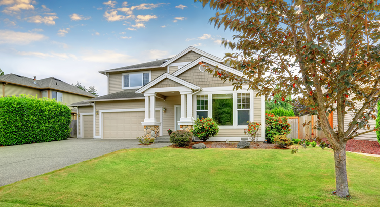 suburban house with grey siding and white trim against a blue sky