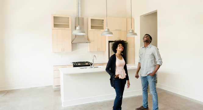 millenial couple standing in empty kitchen looking at the ceiling