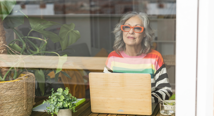Elderly woman with laptop computer looking out a window